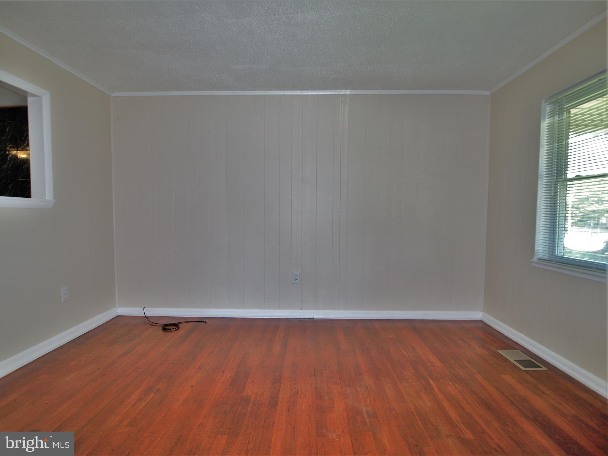 652 Charraway Road Baltimore, MD 21229 - Photo 6 of 22 a view of an empty room with wooden floor and a window