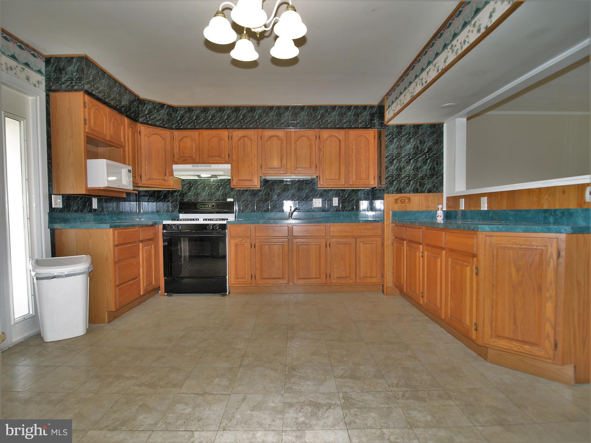 652 Charraway Road Baltimore, MD 21229 - Photo 9 of 22 a kitchen with stainless steel appliances a stove a sink a microwave a dining table and chairs