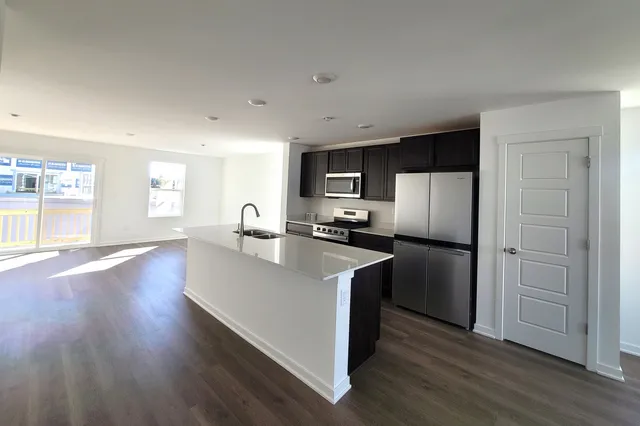 a kitchen with stainless steel appliances granite countertop a refrigerator a sink dishwasher a stove and a wooden floors