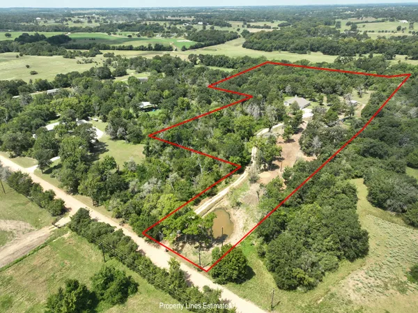 an aerial view of residential houses with outdoor space and trees