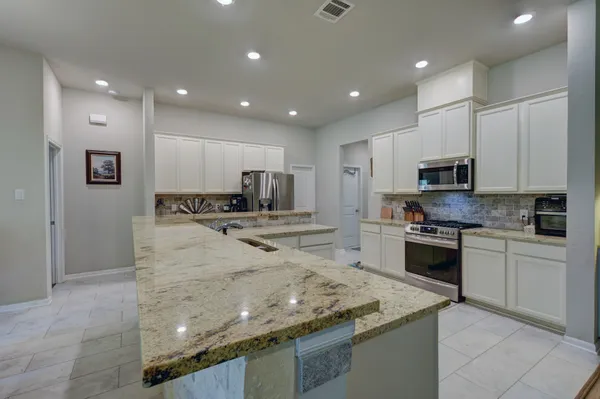 a kitchen with kitchen island granite countertop a stove sink and microwave