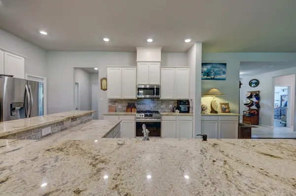 a large kitchen with stainless steel appliances kitchen island granite countertop a large counter top and view of living room