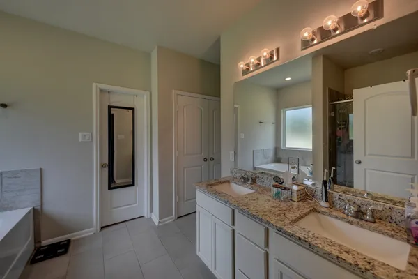 a bathroom with a granite countertop double vanity sink and a mirror