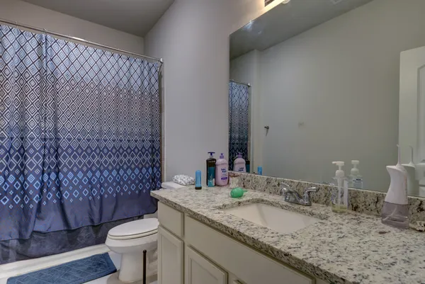 a bathroom with a granite countertop sink mirror vanity and toilet