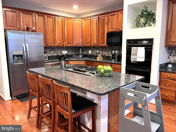 a kitchen with stainless steel appliances a dining table chairs refrigerator and a sink