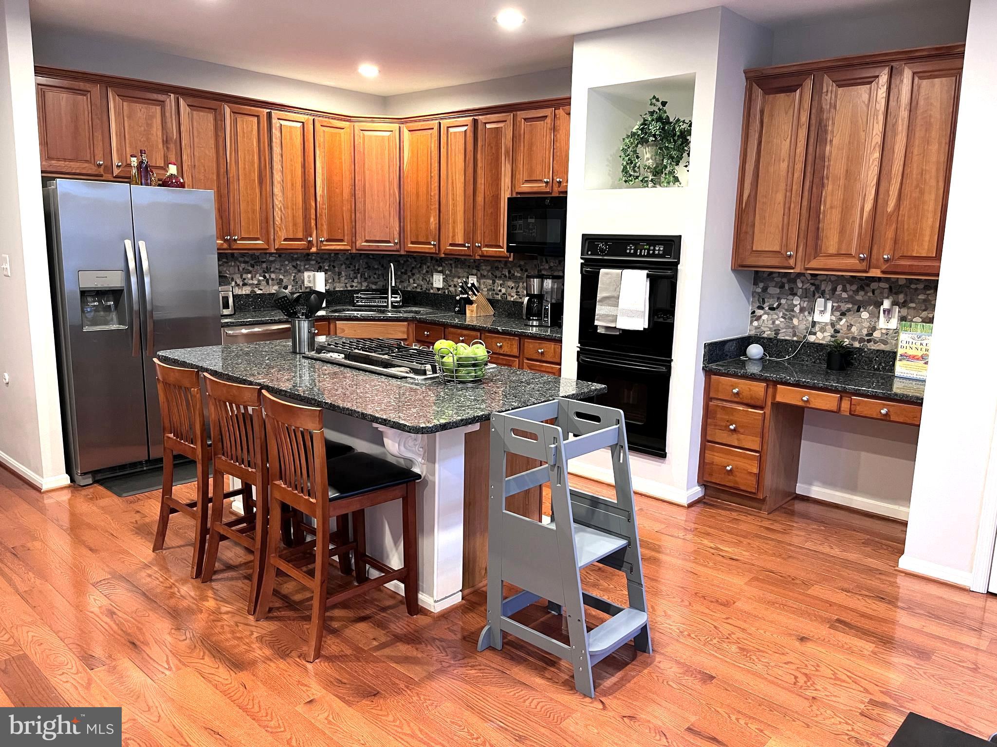 7358 Bloomington Court Springfield, VA 22150 - Photo 13 of 69 a kitchen with stainless steel appliances granite countertop a stove a refrigerator a sink a dining table and chairs with wooden floor
