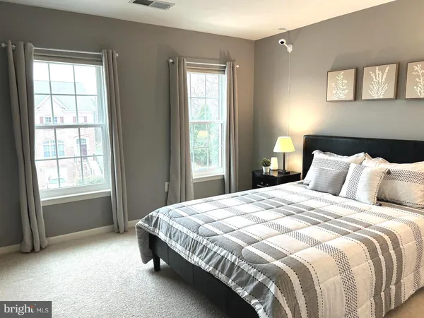 a bedroom with a bed a table and chair with the wooden floor