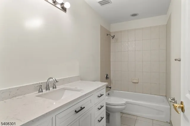 a bathroom with a granite countertop sink a toilet and shower