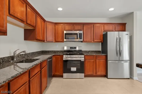a kitchen with stainless steel appliances granite countertop a refrigerator stove top oven and sink