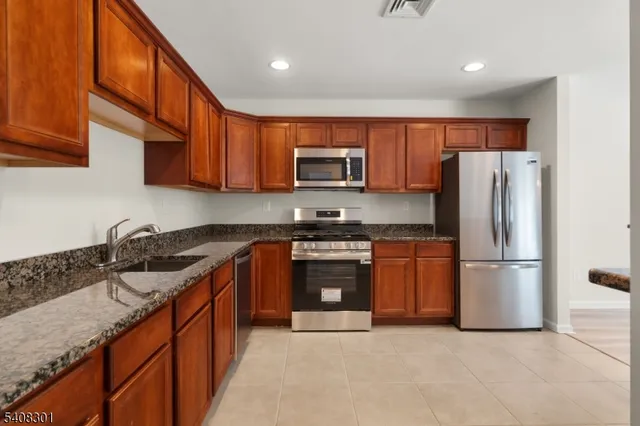 a kitchen with stainless steel appliances granite countertop a refrigerator stove top oven a sink and dishwasher