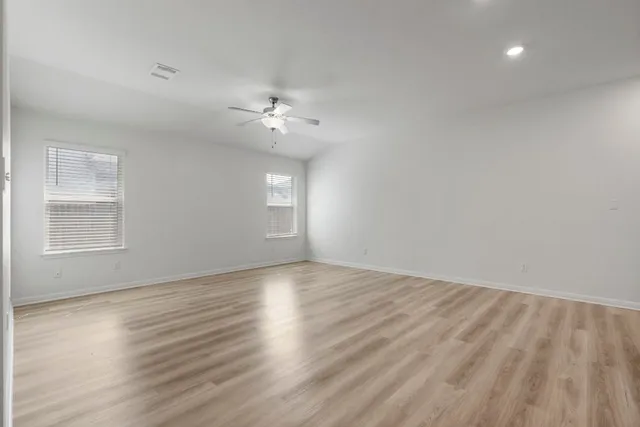 a view of empty room with wooden floor and fan