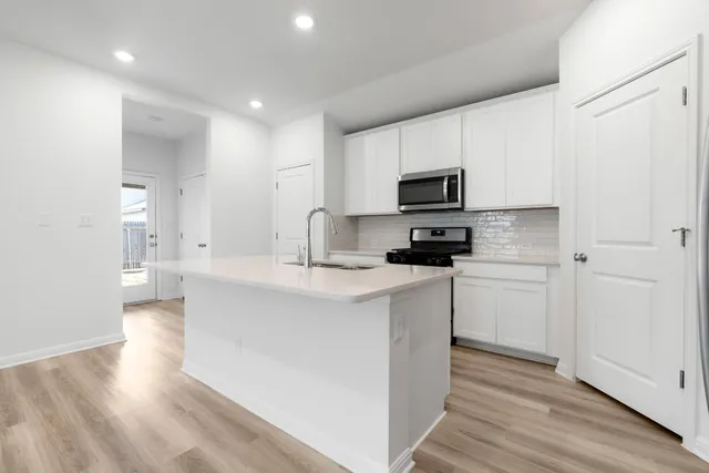 a kitchen with kitchen island a sink dishwasher a stove and a refrigerator with wooden floor