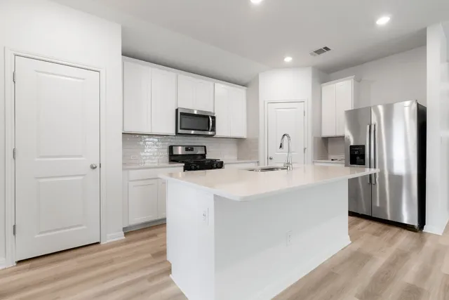 a kitchen with kitchen island a sink stainless steel appliances and refrigerator