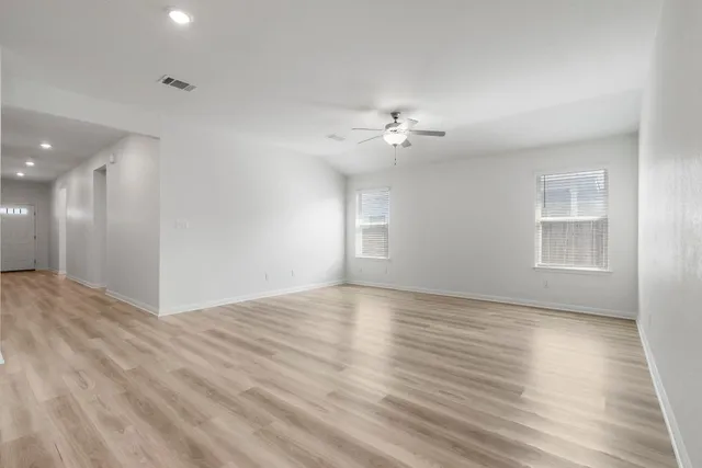 a view of an empty room with a window and wooden floor