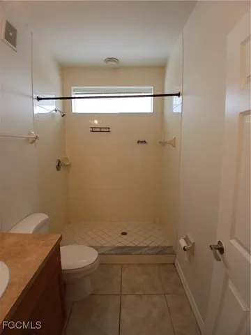 a bathroom with a granite countertop shower a toilet and a sink