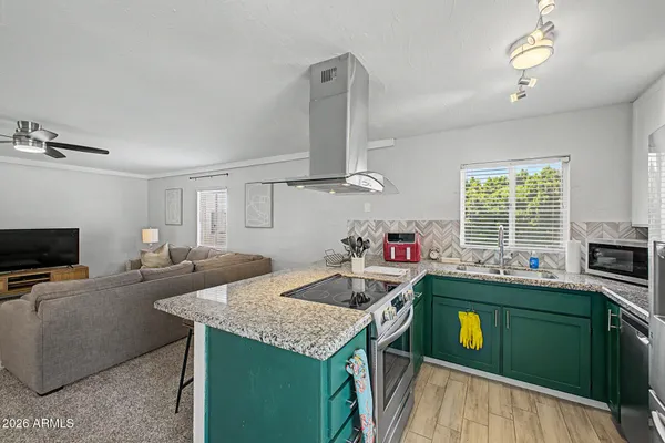 a kitchen that has a sink a microwave oven a stove and white cabinets with wooden floor