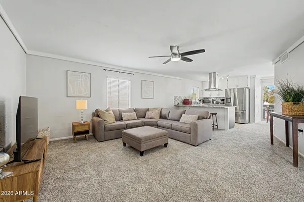 a living room with furniture a ceiling fan and a flat screen tv