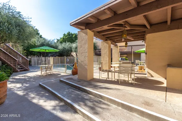 a view of a patio with a table and chairs under an umbrella with a small yard