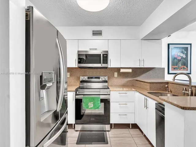 a kitchen with stainless steel appliances granite countertop a refrigerator sink and stove