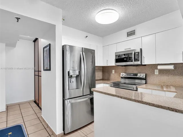 a kitchen with stainless steel appliances granite countertop a refrigerator a stove a microwave and a sink