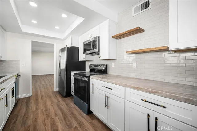 a kitchen with stainless steel appliances granite countertop a refrigerator a stove and a wooden floors