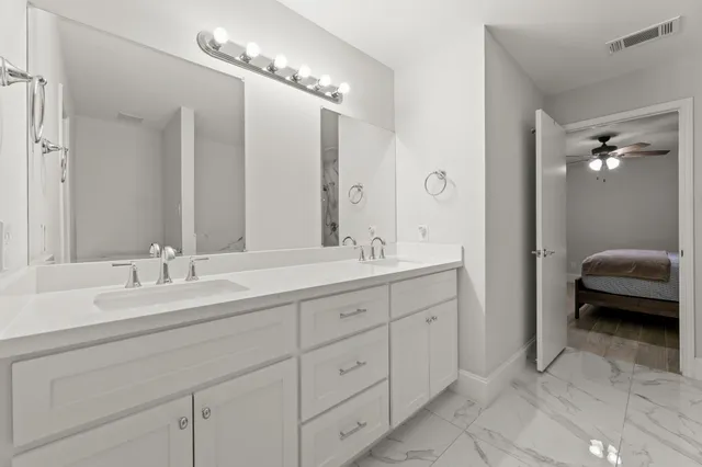 a spacious en suite bathroom with double sink and mirrors