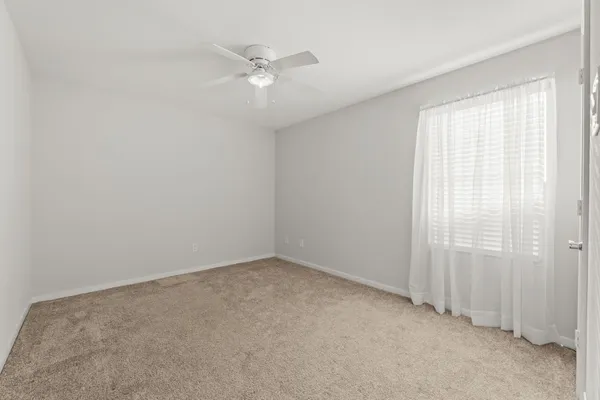 an empty room with windows and fan