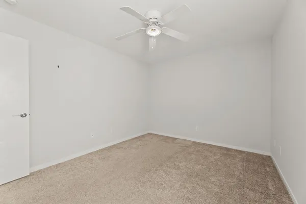 an empty room with a ceiling fan and a window