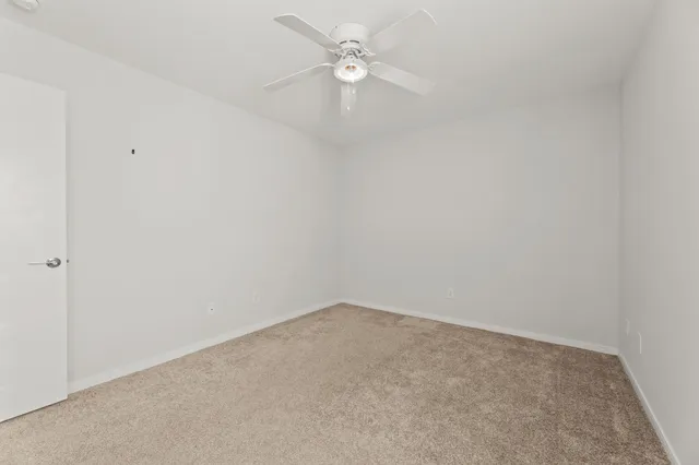 an empty room with a ceiling fan and a window