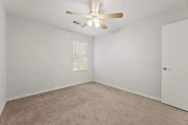 an empty room with windows and chandelier fan