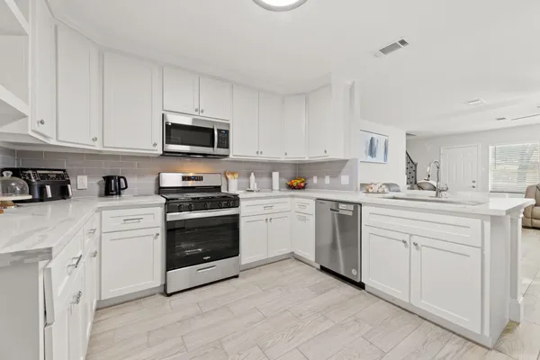a kitchen with white cabinets and stainless steel appliances