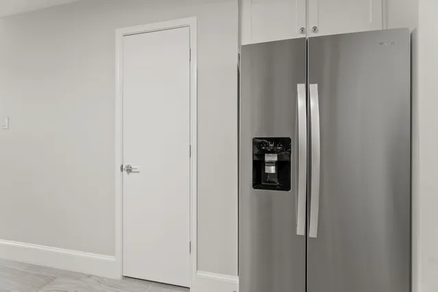 a view of a refrigerator in kitchen and white cabinets