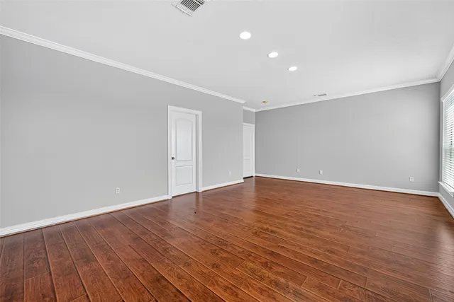 a view of an empty room with wooden floor and closet