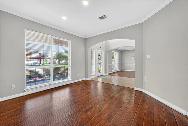 a view of empty room with wooden floor and fan