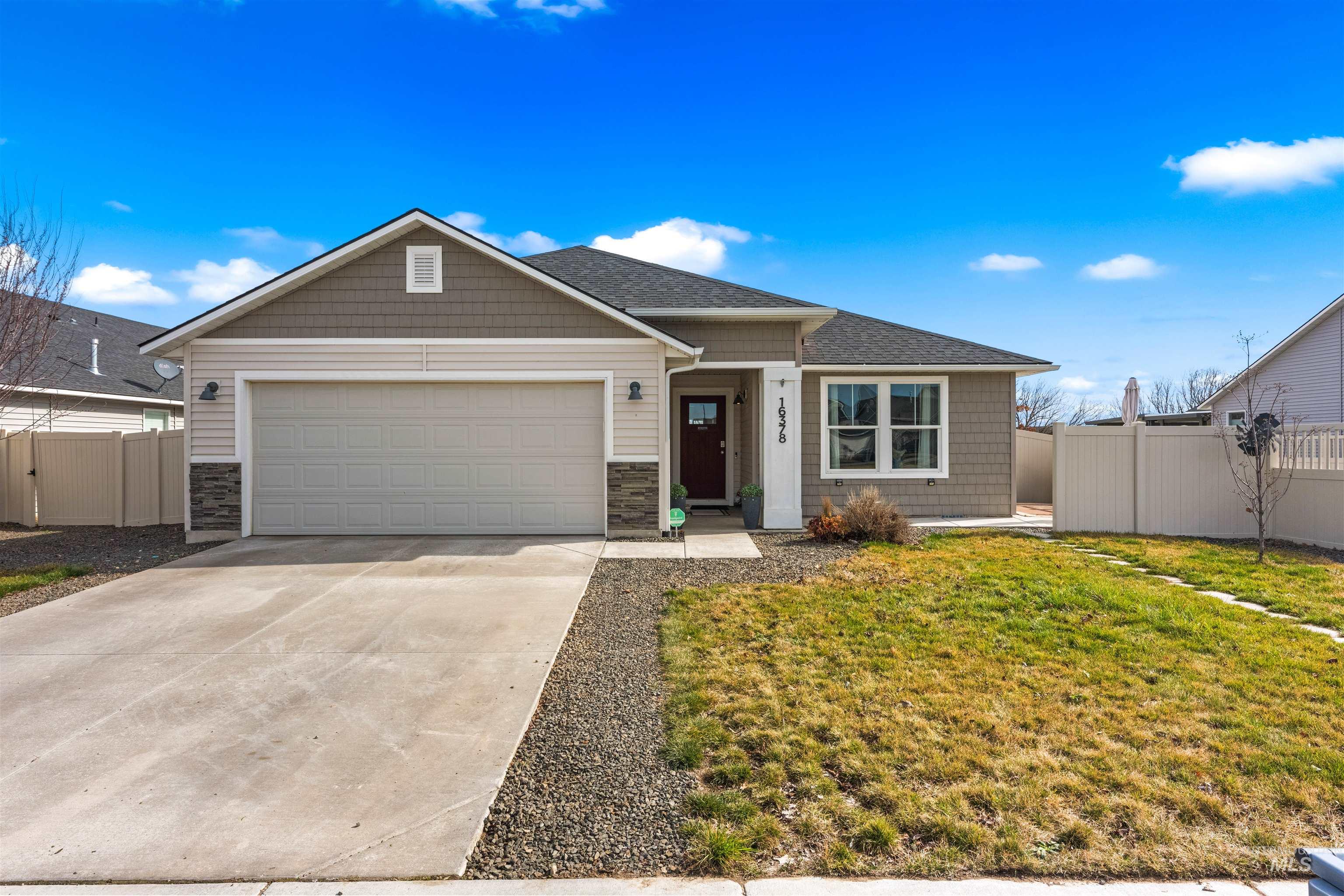 View of front of property with concrete driveway, an attached garage, stone siding, and roof with shingles