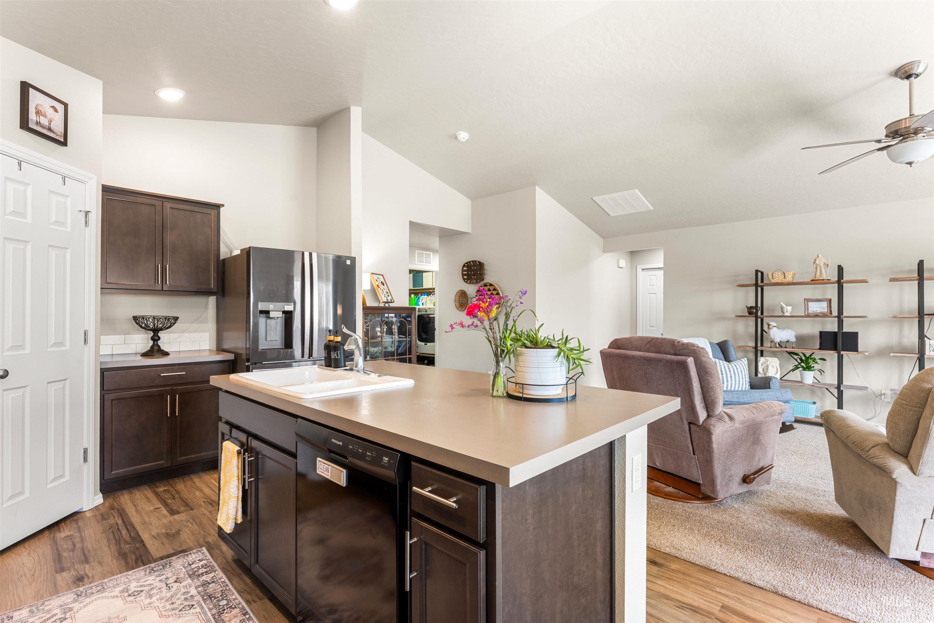 16378 Kelso Way Caldwell, ID 83607 - Photo 34 of 34 Kitchen with dark wood finish cabinets, open floor plan, stainless steel fridge, dishwasher, and vaulted ceiling