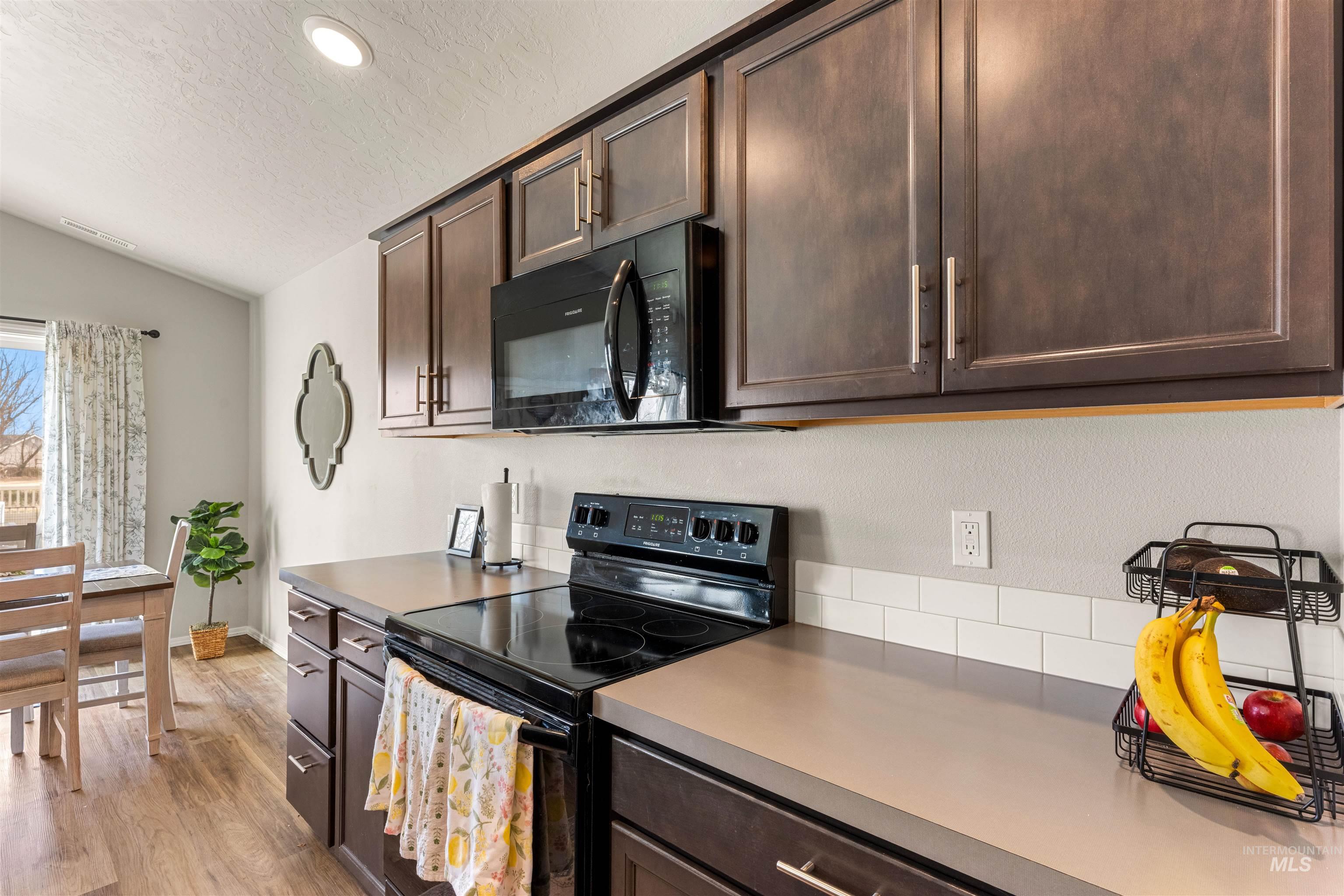 16378 Kelso Way Caldwell, ID 83607 - Photo 14 of 34 Kitchen with black appliances, dark wood finish cabinetry, light wood-style flooring, light countertops, and recessed lighting