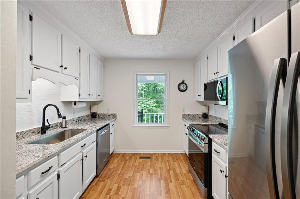 687 Cotton Road Canton, GA 30115 - Photo 13 of 38 a kitchen with stainless steel appliances a sink a stove a refrigerator and cabinets