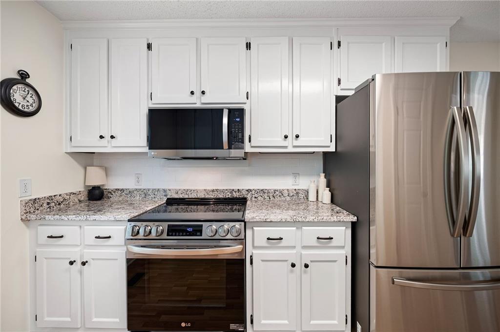 687 Cotton Road Canton, GA 30115 - Photo 15 of 38 a kitchen with stainless steel appliances granite countertop a stove a refrigerator and a white cabinets