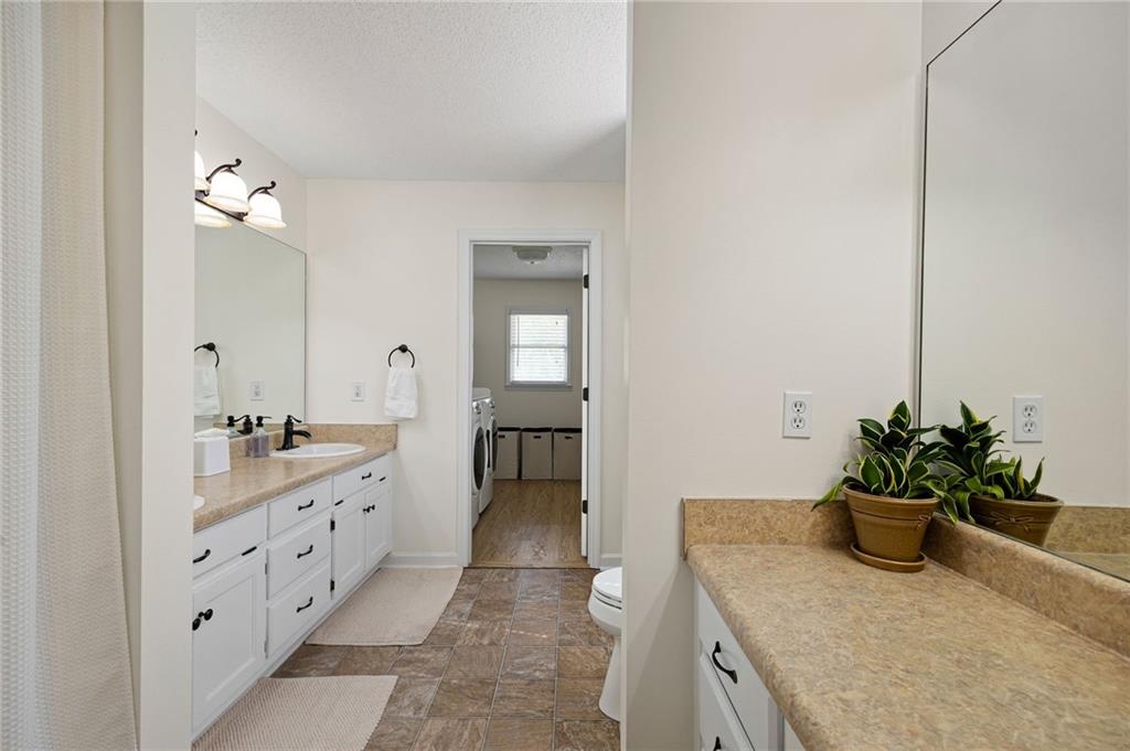 687 Cotton Road Canton, GA 30115 - Photo 21 of 38 a bathroom with a granite countertop sink a mirror and a shower