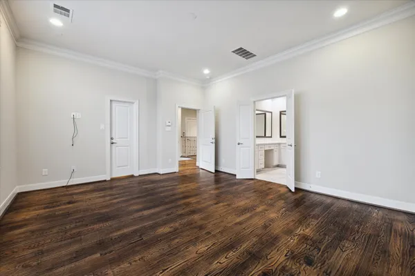 a view of empty room with wooden floor and kitchen