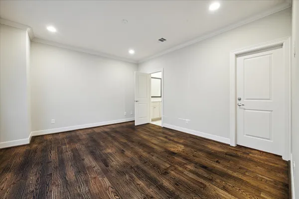 a view of an empty room with wooden floor and closet