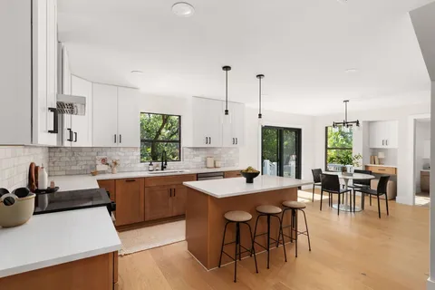 a kitchen with stainless steel appliances granite countertop table chairs sink and cabinets