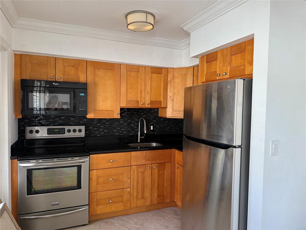a kitchen with granite countertop a refrigerator stove and microwave