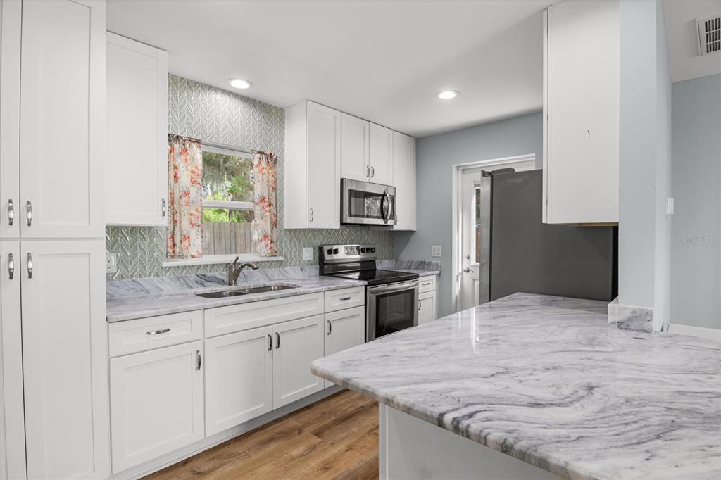 4020 Connersville Road Bartow, FL 33830 - Photo 43 of 50 a kitchen with stainless steel appliances granite countertop white cabinets a refrigerator a sink a stove a microwave and wooden floor