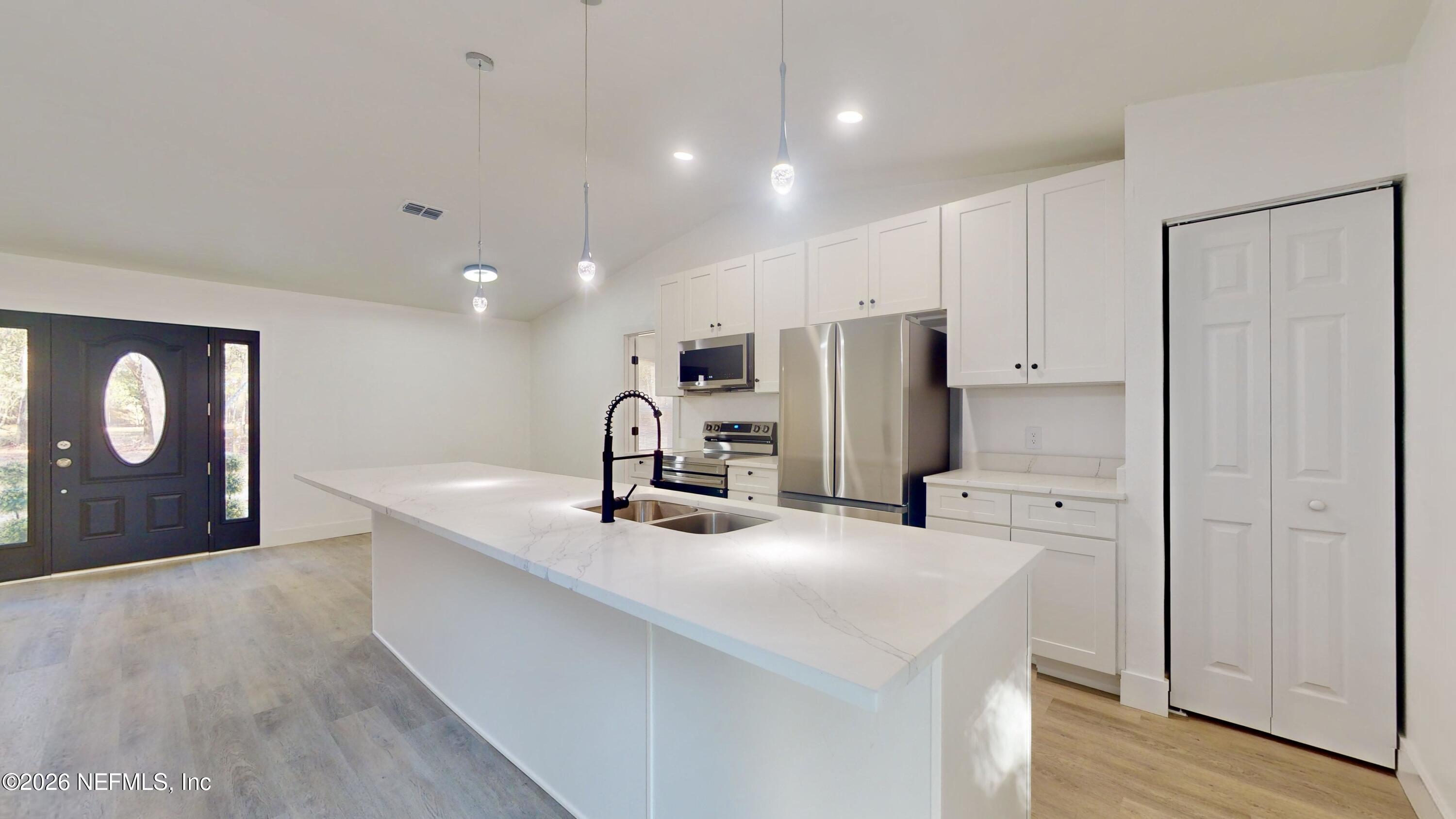 4774 Leopard Circle Middleburg, FL 32068 - Photo 13 of 50 a kitchen with stainless steel appliances kitchen island granite countertop a refrigerator a sink and white cabinets with wooden floor