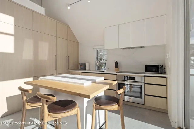 a kitchen with stainless steel appliances a table and chairs in it