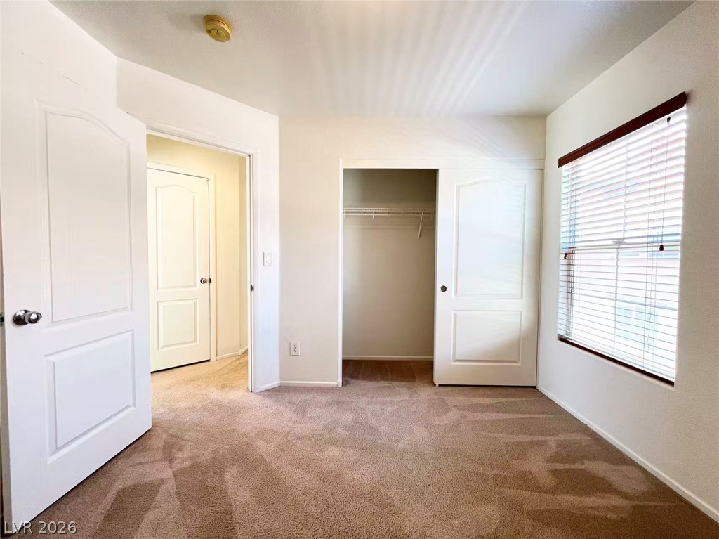 11143 Ranch Valley Street Las Vegas, NV 89179 - Photo 18 of 23 A well-lit bedroom features plush carpeting, a window for natural light, and a convenient walk-in closet.