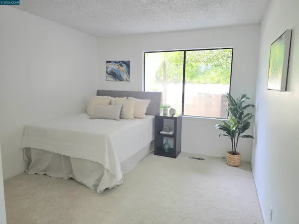 a bed sitting in a spacious bedroom next to a window