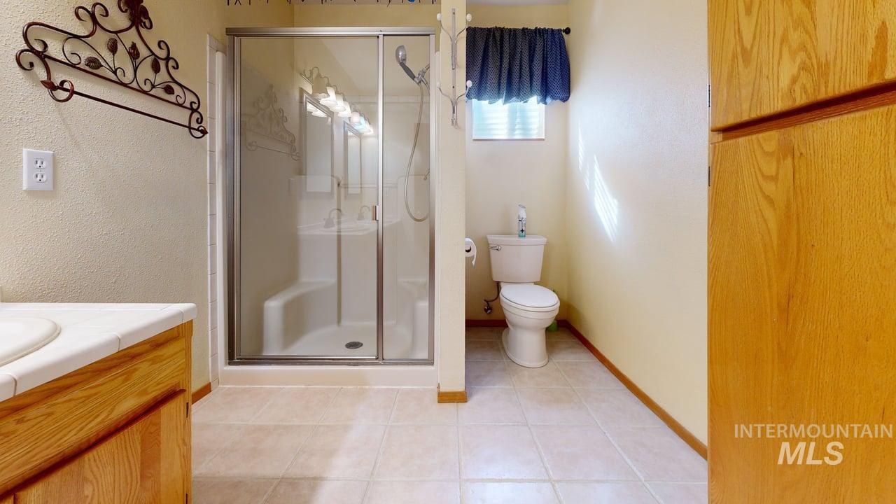 2794 9th Avenue Clarkston, WA 99403 - Photo 21 of 34 Bathroom with vanity, a stall shower, light tile patterned flooring, and a textured wall